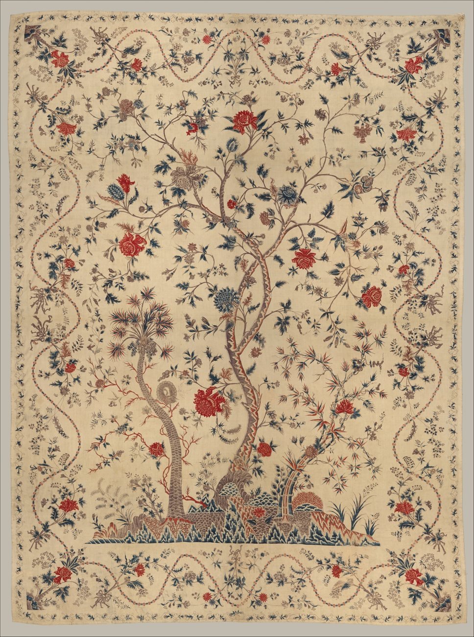 A hand-painted Indian cotton hanging with a flowering tree of life on a cream ground, framed by a border of flowering vines.